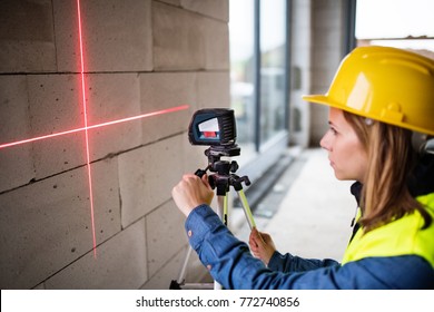 Young Woman Worker With Laser On The Building Site.