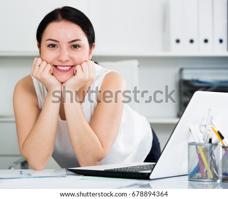 Young woman worker posing gracefully while working in office