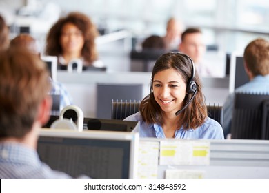 Young woman working in call centre, surrounded by colleagues - Shutterstock ID 314848592