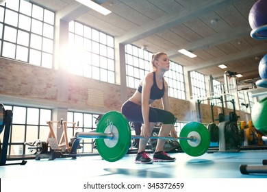 Young Woman Working Hard In The Gym. Fit Female Athlete Lifting Weights In Health Club.