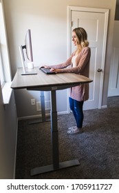 Young Woman Working At Her Standing Desk In Her Home Office On Her Computer