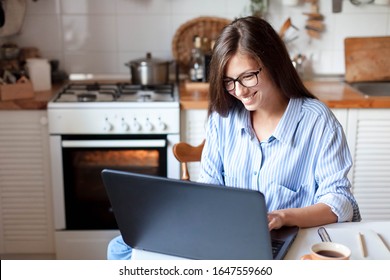 Young Woman Working From Home Office. Freelancer Using Laptop And The Internet For Shopping Online. Happy Girl Smiling. Workplace In Cozy Kitchen. Successful Female Business. Lifestyle Moment.