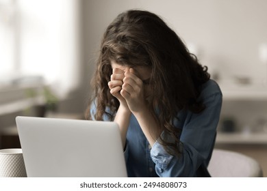 Young woman working from home office, feel stressed and frustrated, covering her face with hands sit in front of laptop, looks tensed and anxious, faced with difficulties, feels overworked and burnout - Powered by Shutterstock