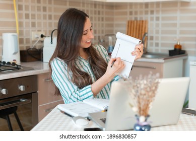 Young Woman Working From Home And Showing Diagram On Web Cam