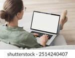 Young woman working at home, using laptop computer with blank white screen display mockup. Student girl looking at laptop screen