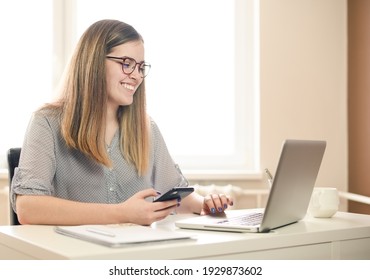  young woman working from home using smart phone and computer, woman's hands using smart phone in interior, at home workplace using technology, credit card. High quality photo
