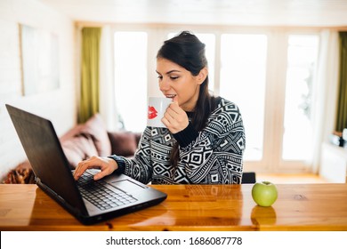 Young Woman Working From Home.Home Office.Quarantined Employee.Casual Working Environment.Morning Routine.Entepreneur Checkinh Email While Dringking Coffee.Freelancer Working On A Project