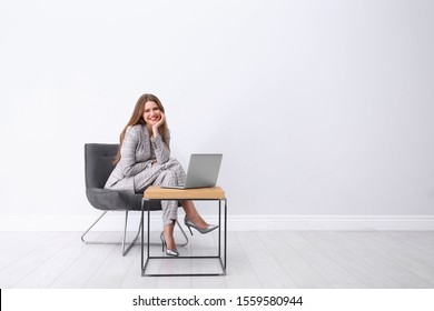Young woman working with laptop in armchair indoors. Space for text - Shutterstock ID 1559580944