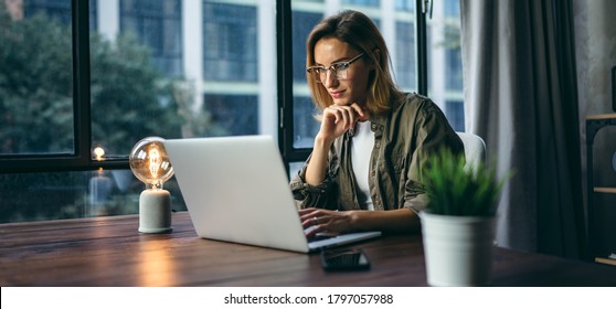 Young woman working with a laptop. Female freelancer connecting to internet via computer. Blogger or journalist writing new article. - Shutterstock ID 1797057988