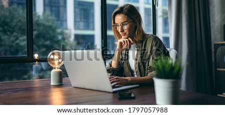 Young woman working with a laptop. Female freelancer connecting to internet via computer. Blogger or journalist writing new article.