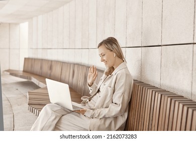 A young woman is working at a laptop in the park. The concept of remote work via the Internet. A freelancer works in the park