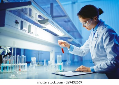 Young woman working with liquids in glassware - Shutterstock ID 329432669