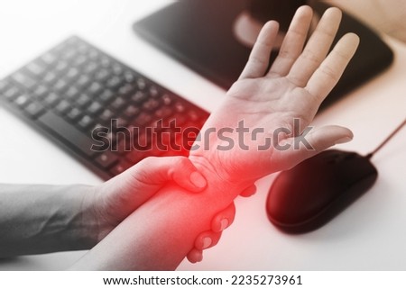 Young woman working in office with a carpal tunnel syndrome or wrist joint inflammation