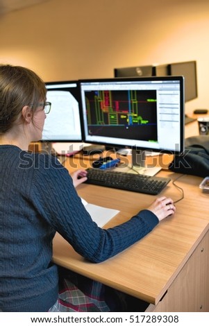 Young woman working in office on computer. Female architect in glasses designing building