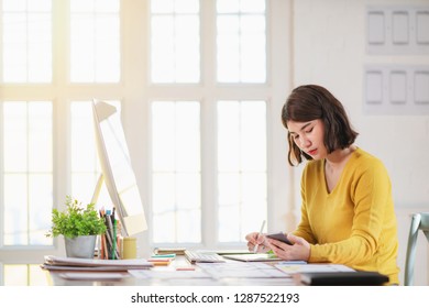 Young woman working in office, sitting at desk, using computer.