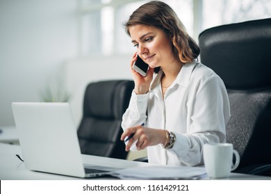 Young Woman Working In Office Talking On A Cell Phone