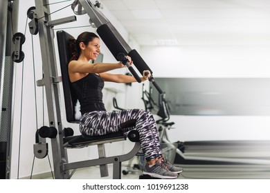 Young Woman Working On Chest Press In Gym