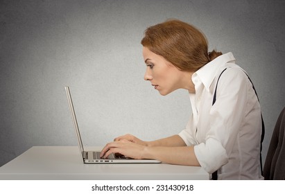 Young Woman Working On Computer Sitting At Desk Isolated On Grey Wall Gloomy Office Background With Copy Space. Long Monotonous Tiresome Working Hours Life Concept