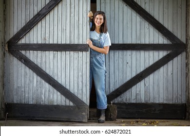 Young Woman Working On A Farm Is Opening The Door Of A Barn Or Shed