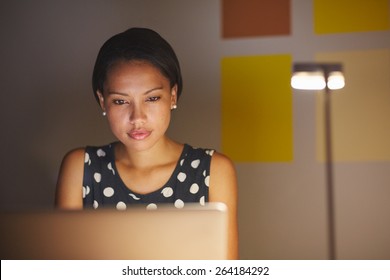 A Young Woman Working On Her Laptop In Her Office At Night