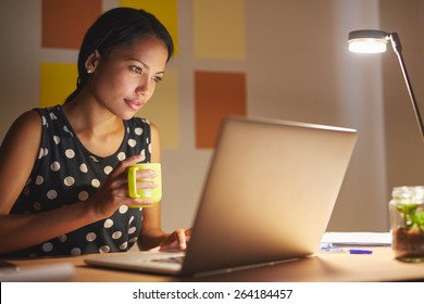 A Young Woman Working On Her Laptop In Her Office At Night