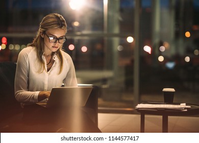Young woman working on the laptop late at night. Caucasian businesswoman working overtime in the office to finish the project within the deadline.