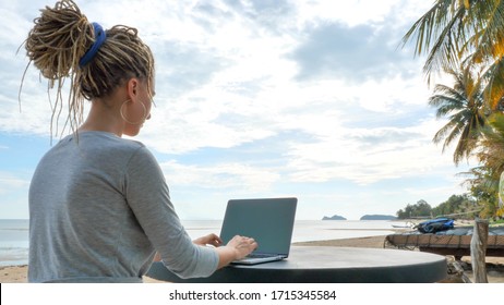 Young Woman Working On Laptop At Sand Beach Of Tropical Island. Freelance Outdoor Work Concept
