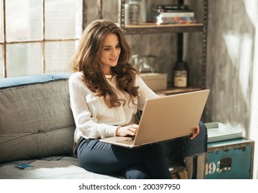 Young Woman Working On Laptop In Loft Apartment