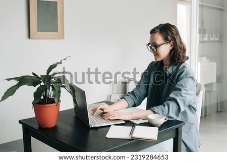 Young woman working on laptop in modern office. Student girl studying or freelancing from home. Work-from-home, business, and lifestyle concept. Technology, productivity, education, and remote work.