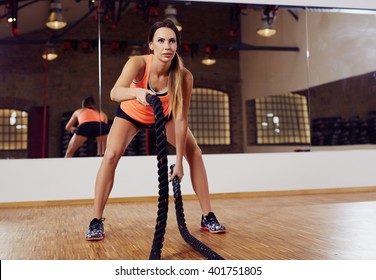 Young woman working out with battle ropes at a gym