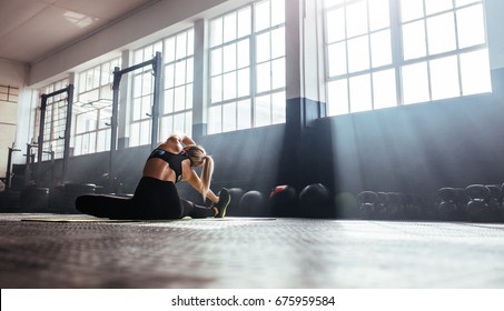 Young woman working out in gym. Back view of woman doing stretching exercise in the morning sunlight at the gym. - Powered by Shutterstock