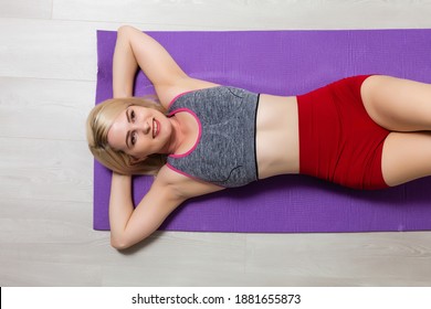 Young Woman Working Out On A Mat In A Gym Lying On Her Back With Her Hands On Her Stomach Doing Breathing Exercises In A Low Angle Head Down View