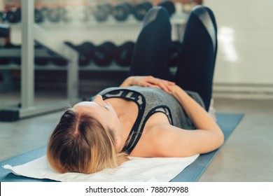 Young Woman Working Out On A Mat In A Gym Lying On Her Back With Her Hands On Her Stomach Doing Breathing Exercises In A Low Angle Head Down View