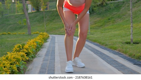 Young Woman Working Out In The Park, Holding Her Injured Knee In Slow Motion.