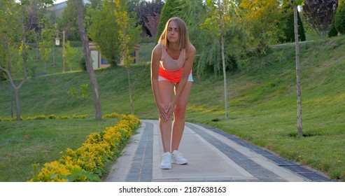 Young Woman Working Out In The Park, Holding Her Injured Knee In Slow Motion.