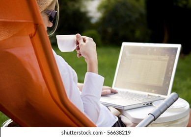 Young Woman Working Outside On Computer And Drinking Coffee