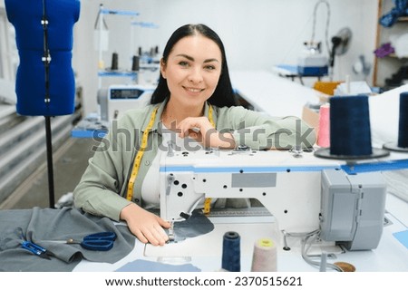 Young woman working as seamstress in clothing factory