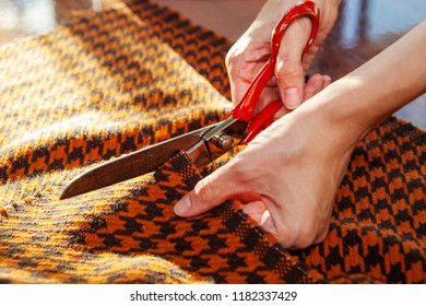 Young woman working in a sewing studio: cutting fabric with scissors. Fashion designers atelier   