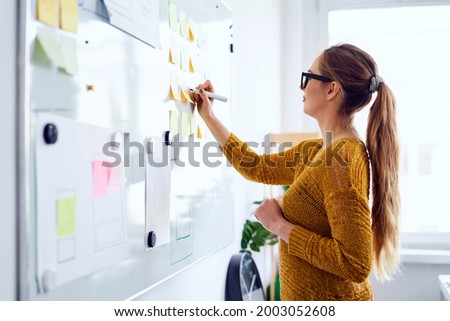 Young woman working in startup office writing on whiteboard