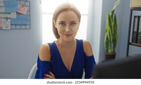 Young woman in a workplace with a blue dress and red hair, sitting confidently indoors in an office setting. - Powered by Shutterstock