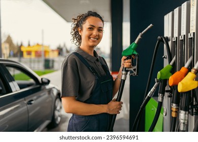 A young woman works at a gas station, holding a fuel hose