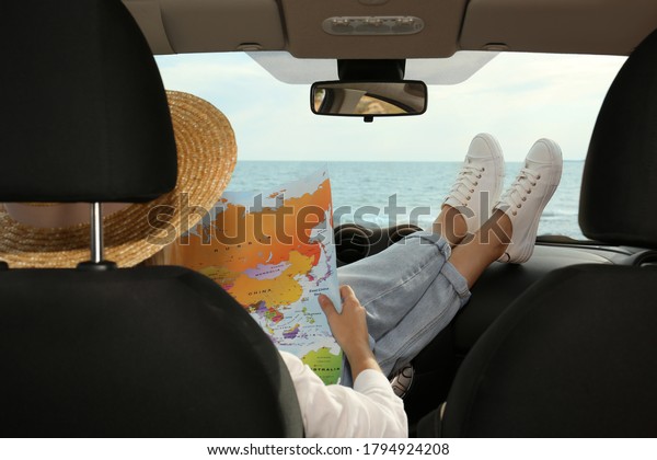 Young\
woman with world map in car, back view. Road\
trip