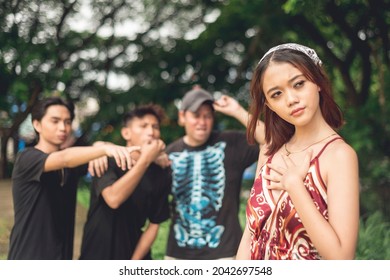 A young woman is worried about three rude men catcalling and making provocative gestures from behind. Street harassment concept.