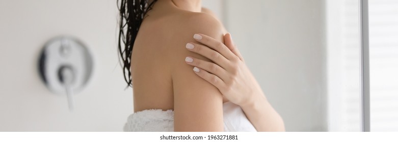 Young Woman Wrapped In Bath Towel Touching Shoulder Soft Skin, Enjoying Cosmetic Effect Of Moisturizing Soap, Applying Lotion After Taking Shower.  Banner