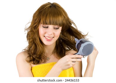 Young woman wrapped in yellow towel using hair drier, isolated on white background