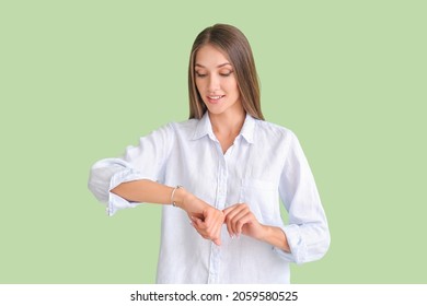 Young woman with wristwatch on color background