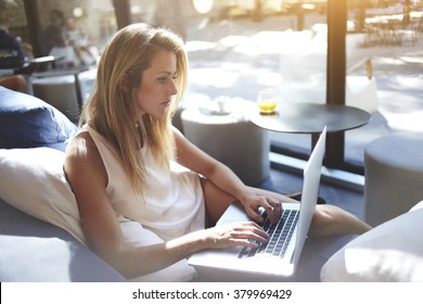 Young Woman Writer Keyboarding Text For A New Book Via Laptop Computer While Sitting In Co-working Cafe,pretty Female Student Searching Information On Net-book During Lunch Break In Modern Coffee Shop