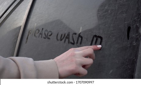 A Young Woman Writes With A Finger On A Dirty Car 