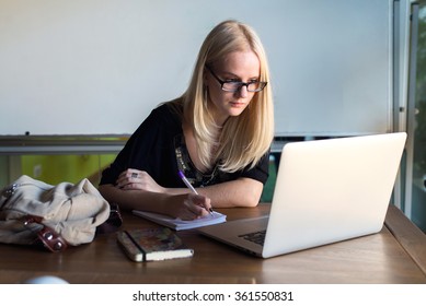 young woman writes something working with laptop 