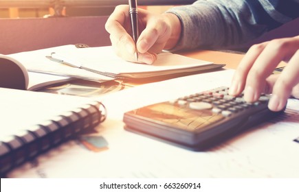 Young woman writing make note and doing calculate finance at home office. - Shutterstock ID 663260914